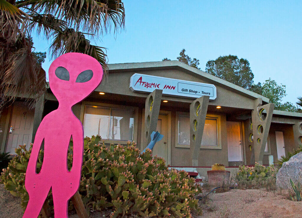 pink alien standing in front of the atomic inn