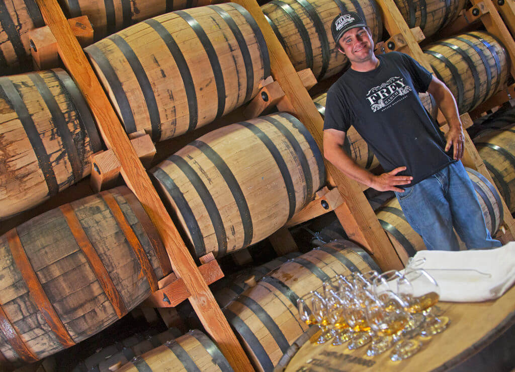 man standing in front of whisky barrels at frey ranch