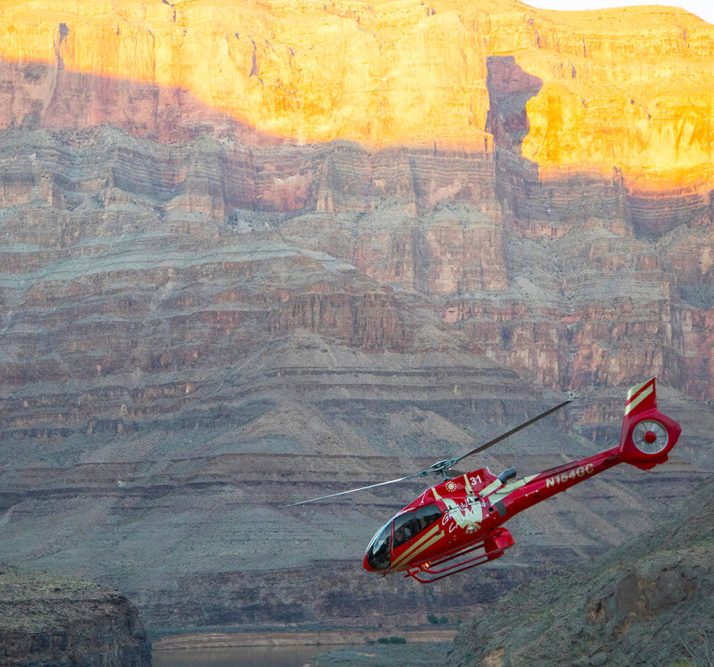 a red helicopter flying over the grand canyon